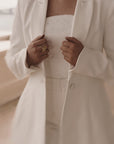 Ivory bridal crepe blazer with curved sleeve hem & covered buttons. Chiffon drape detail