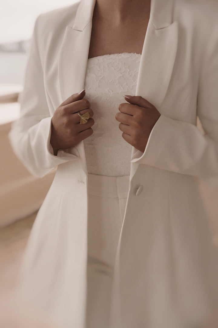 Ivory bridal crepe blazer with curved sleeve hem & covered buttons. Chiffon drape detail
